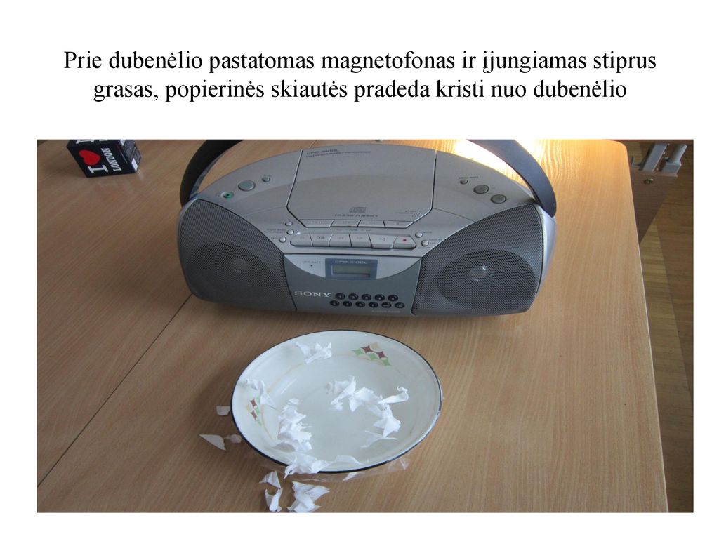 Prie dubenėlio pastatomas magnetofonas ir įjungiamas stiprus grasas, popierinės skiautės pradeda kristi nuo dubenėlio